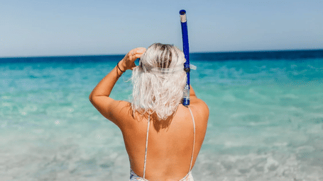 Woman standing at the edge of the sea with a snorkel, gazing at the ocean | Tamarind Hills Resort and Villas - Antigua